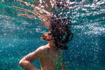 Menino anônimo em máscara de mergulho snorkeling em água borbulhante de mar azul — Fotografia de Stock