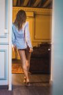 Vista posteriore della donna sessuale in camicia in piedi sulla porta — Foto stock