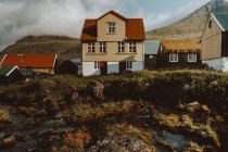 Acogedoras casas de pueblo tradicionales en las colinas y el río en la isla de Feroe - foto de stock