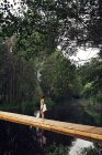 Молода жінка йде мостом через річку — стокове фото