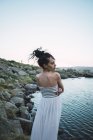 Молода жінка в елегантній сукні, що стоїть біля розривного озера — стокове фото
