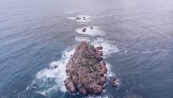 Malerischer Drohnenblick auf Meerwasser, das um eine kleine Klippe in Asturien spritzt, Spanien — Stockfoto