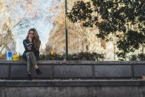 Young woman reading book on stairs in city park — Stock Photo