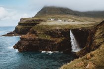 Scogliere rocciose verdi e cascata a spruzzo sulle isole Feroe — Foto stock