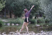 Menina de cabelos vermelhos executa exercícios pelo rio — Fotografia de Stock