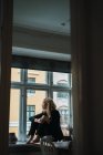 Romantique blonde jeune femme assise sur le rebord de la fenêtre — Photo de stock