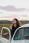 Woman leaning on a vintage car in countryside — Stock Photo