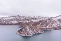 Atemberaubende Aussicht auf majestätische Hügel mit Schnee bedeckt in der Nähe ruhigen Wassers an bewölkten Tag in Asturien, Spanien — Stockfoto