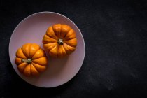 Halloween decoration of pumpkins on plate on dark background with copy space. — Stock Photo