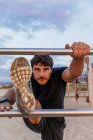 Selbstbewusster bärtiger Läufer streckt sich auf Leiter am Strand — Stockfoto