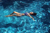 Femme couchée sur de l'eau bleue transparente — Photo de stock