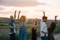 Gruppo di giovani in abiti casual ridere e ballare divertendosi nella splendida campagna insieme — Foto stock
