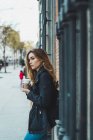 Молода жінка папір чашкою ароматної кави стоячи на вулиці — стокове фото