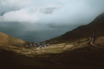 View to small village between green mountains under dark clouds on Feroe Islands — Stock Photo