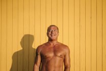 Homem mais velho muscular coloca fundo amarelo — Fotografia de Stock