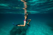 Niño anónimo haciendo snorkel en agua de mar azul - foto de stock