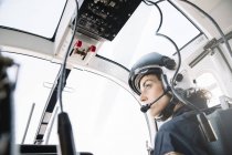 Pensive female pilot sitting and operating in helicopter — Stock Photo