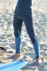 Giovane uomo in neoprene e in piedi in spiaggia — Foto stock