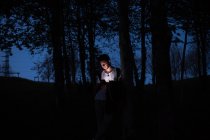 Man using smartphone in dark forest — Stock Photo