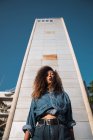 Молодая женщина в джинсовой одежде стоит напротив высокого здания — стоковое фото