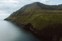 Océano y verde pintoresco acantilado en las Islas Feroe - foto de stock