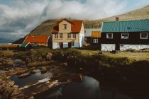 Acogedoras casas de pueblo tradicionales en las colinas y el río en la isla de Feroe - foto de stock