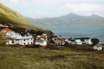 Vista al pequeño pueblo con casas coloridas y montañas verdes en las Islas Feroe - foto de stock