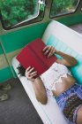 Woman lying inside retro caravan and reading book — Stock Photo