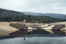 Giovane donna in piedi sulla roccia vicino all'acqua — Foto stock