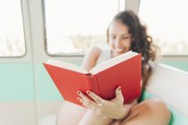 Close-up of woman sitting inside caravan and reading book — Stock Photo