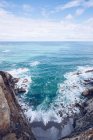 Incredibile vista di acqua di mare spruzzi vicino a una lunga scogliera rocciosa nella giornata nuvolosa nelle Asturie, Spagna — Foto stock