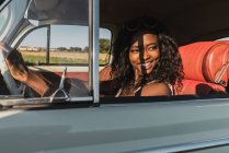 Красивая улыбающаяся африканская американка за рулем автомобиля — стоковое фото
