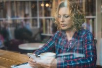 Женщина сидит в кафе с чашкой кофе — стоковое фото