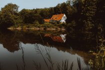 Big house with orange roof built at forest and pond on Feroe Island — Stock Photo