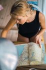 Junge blonde Frau plant Reise mit Karte — Stockfoto