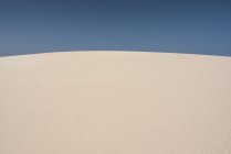 Colinas de areia no deserto árido selvagem com céu azul claro nas ilhas Canárias — Fotografia de Stock