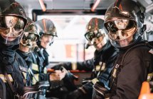 Bomberos irreconocibles con casco en un vehículo de emergencia - foto de stock