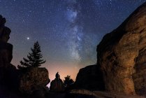 Hombre sentado bajo las estrellas Vía Láctea en las montañas silueta roca. Soria, España - foto de stock