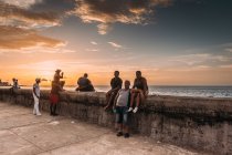 LA HABANA, CUBA - MAIO 1, 2018: moradores da cidade cubana que se refrescam na orla de concreto pedestre no fundo do céu do pôr do sol, — Fotografia de Stock