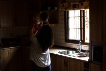 Mujer en la cocina jugando con el bebé - foto de stock