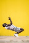 Африканский американец в джинсовом комбинезоне практикующий брейк-данс на жёлтом фоне — стоковое фото