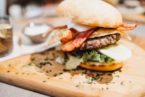 Von oben Nahaufnahme von köstlichen Burger serviert auf Holzbrett mit Eimer mit gebratenen Kartoffelkeilen und Sauce — Stockfoto