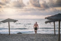 Strong old man walking on the beach — Stock Photo