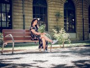 Dreamy woman with bunch of flowers on bench — Stock Photo
