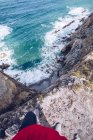Cropped image of person standing on stony cliff over beautiful splashing sea in Asturias, Spain — стокове фото