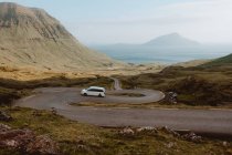 Weißes Auto fährt auf Serpentinenstraße in den Bergen auf Feroe Islands — Stockfoto