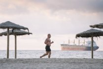 Strong old man makes exercise on the beach — Stock Photo