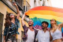 Gruppo di amici gay con una bandiera dell'orgoglio gay sulla strada di Madrid — Foto stock