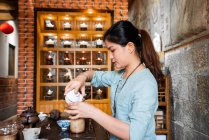 Joven mujer asiática haciendo preparaciones y elaborando té oriental - foto de stock