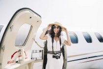 Smiling female traveler with photo camera departing from plane on arrival at airport — Stock Photo